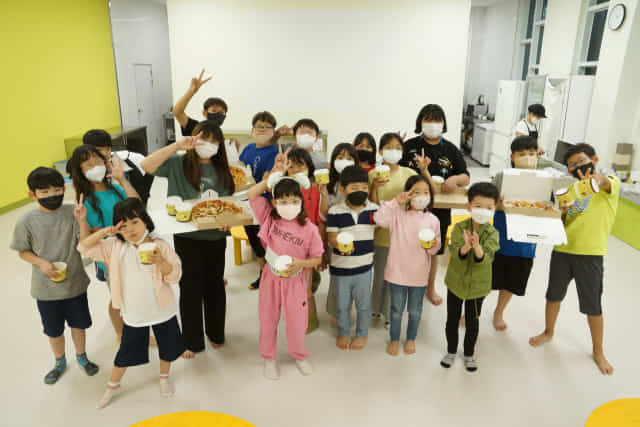 체험에 참여한 아이들이 자신들의 손으로 직접 만든 치즈와 피자를 들고 포즈를 취하고 있다.